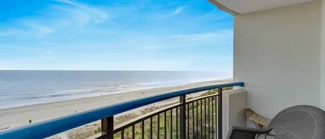 A balcony with a view of the beach and ocean.