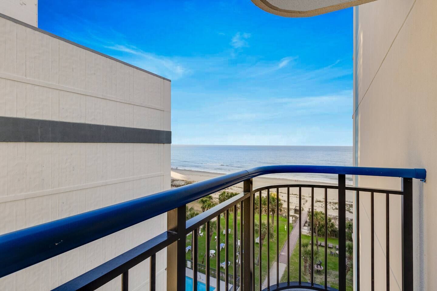 A balcony with a view of the beach and ocean.