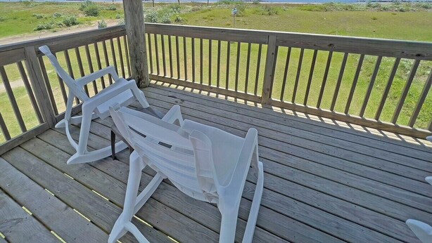 A wooden deck with white plastic chairs and a view of the beach. - Pardners - Beachfront  - Island Realty (Grand Isle)