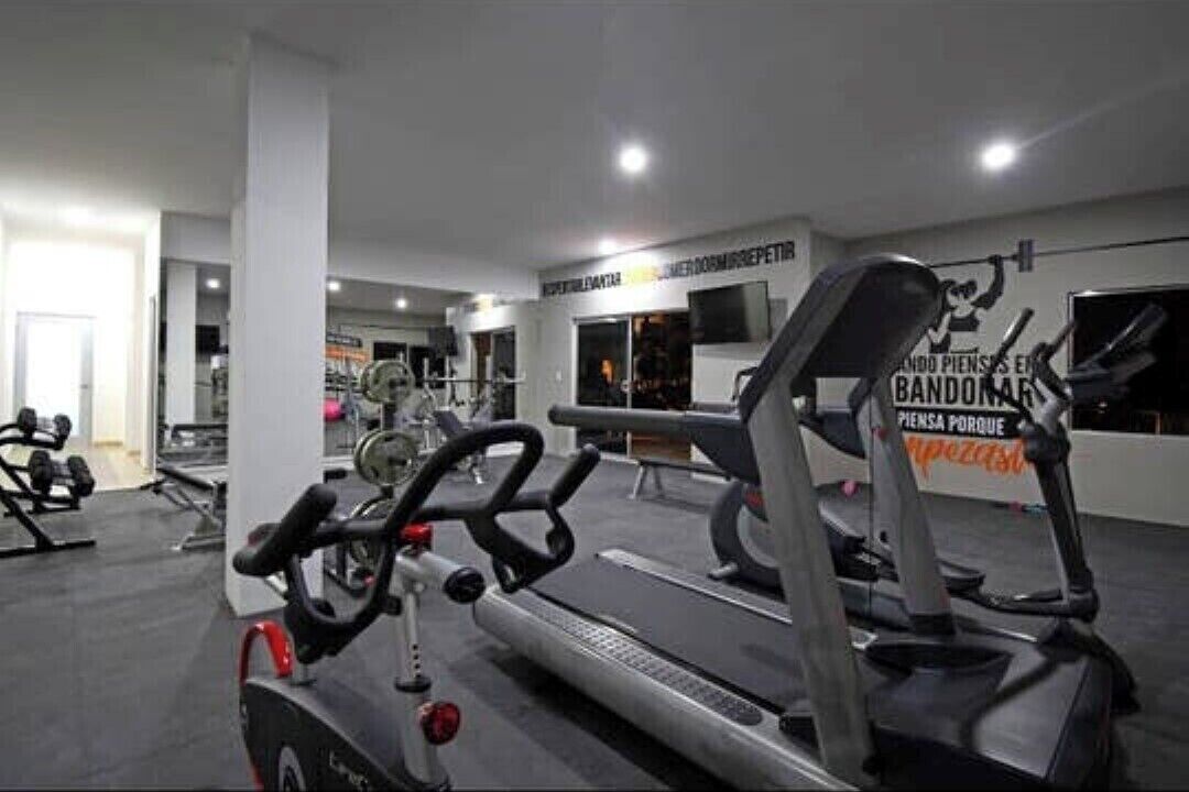 A gym with treadmills, weight machines, and a mirrored wall.