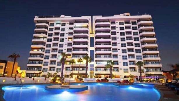 A high-rise hotel with a swimming pool in front. - Master Penthouse lujo y comodidad (La Paz)