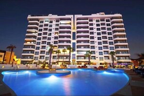 Un hotel de gran altura con una piscina al frente.