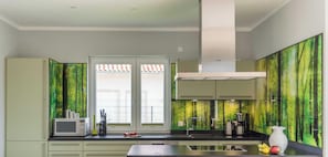 A modern kitchen with a microwave, coffee maker, and fruit on the counter.