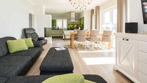 A modern living room with a sofa, ottoman, and dining area.