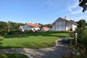 A residential property with a well-maintained lawn, a gravel driveway, and a large house with a red-tiled roof.