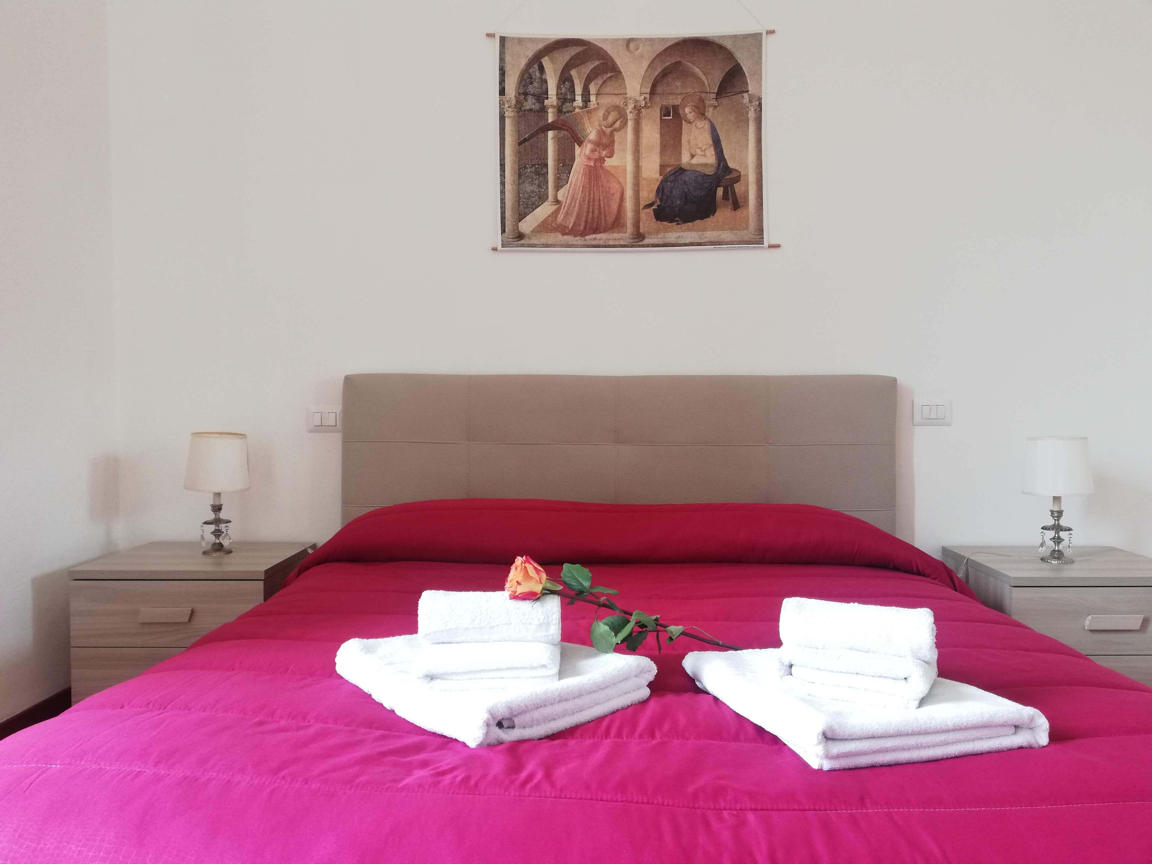 Une chambre d’hôtel avec un lit, deux tables de chevet, un tableau au mur et des serviettes sur le lit.
