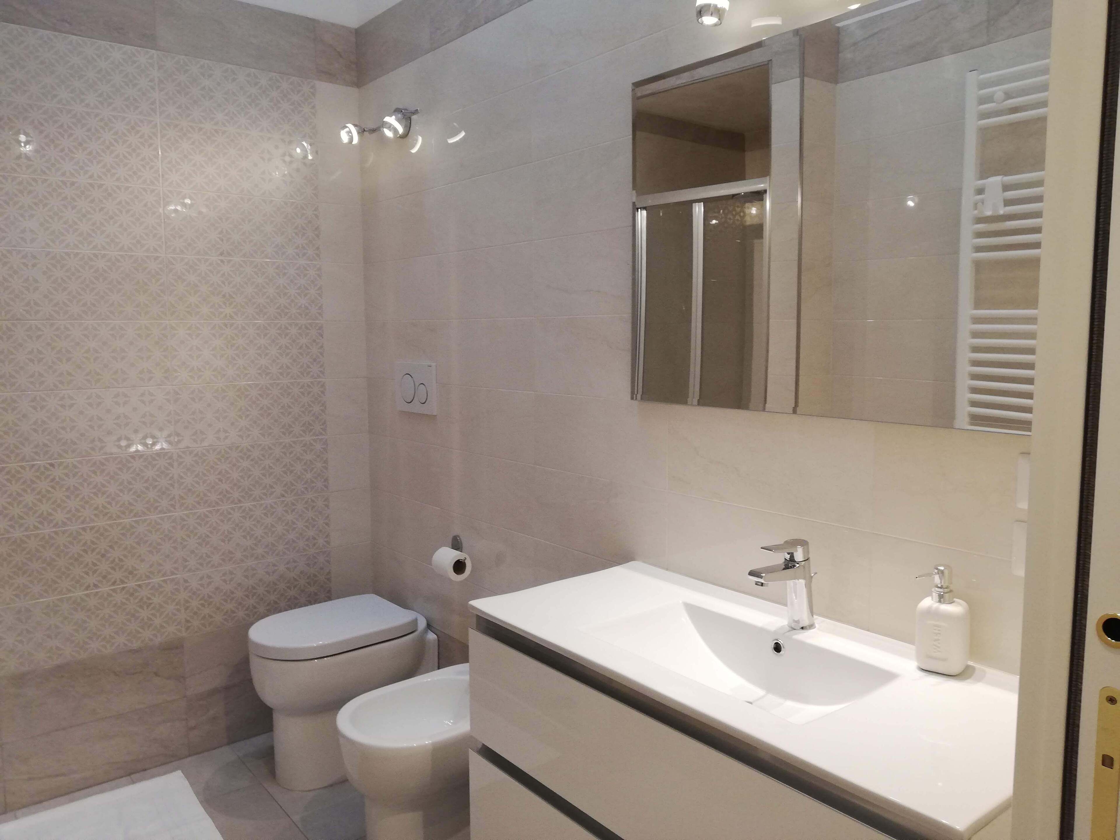 A modern bathroom with a toilet, bidet, and a sink with a mirror above it.