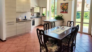 A modern kitchen with a dining area, large windows, and a clock on the wall.