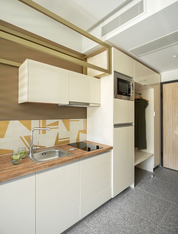 A modern kitchen with a built-in microwave, stainless steel sink, and wooden countertop.
