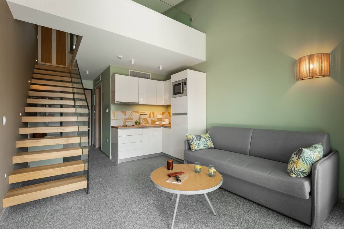A modern interior with a staircase, kitchen, and seating area.