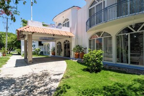 A modern building with a covered entrance, large windows, and a well-maintained lawn. - México Lindo (Santa María Huatulco)
