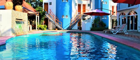 Una piscina al aire libre, sillones reclinables de piscina