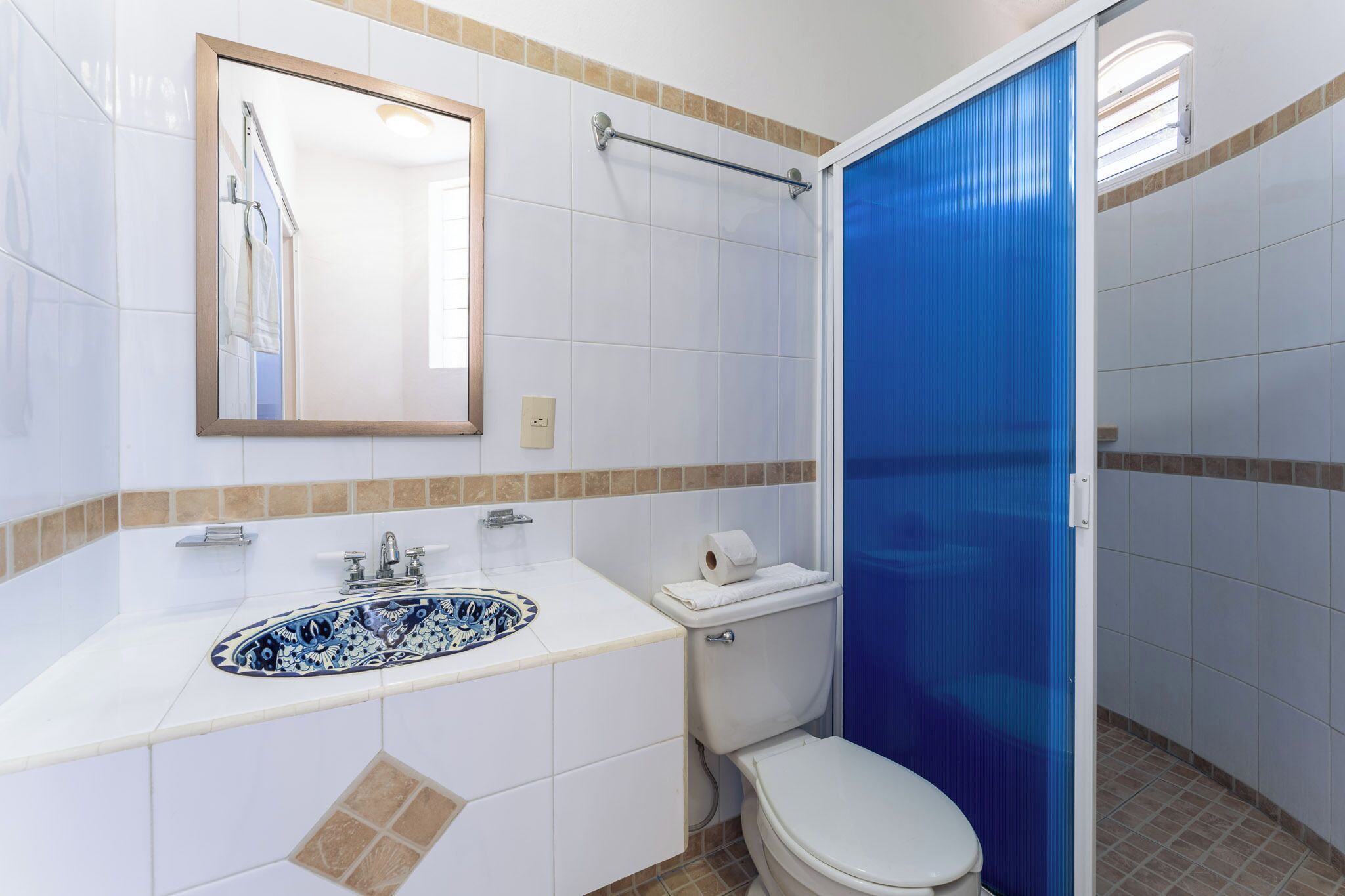 A bathroom with a white sink, a toilet, and a shower with a blue door.