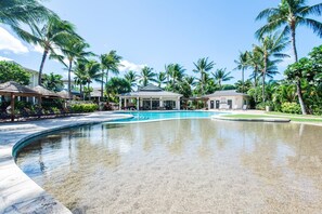 Et resortområde med pool, liggestole og palmer.