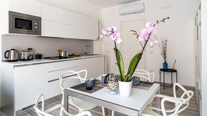 Una cocina moderna con armarios blancos, microondas y comedor con mesa y sillas.