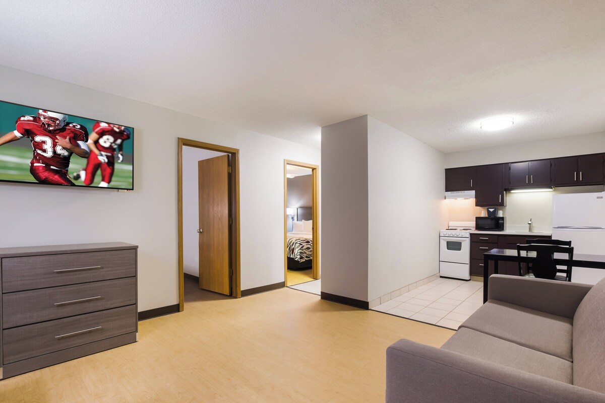 Een modern appartement met een woonkamer, kitchenette en een deur naar een slaapkamer.