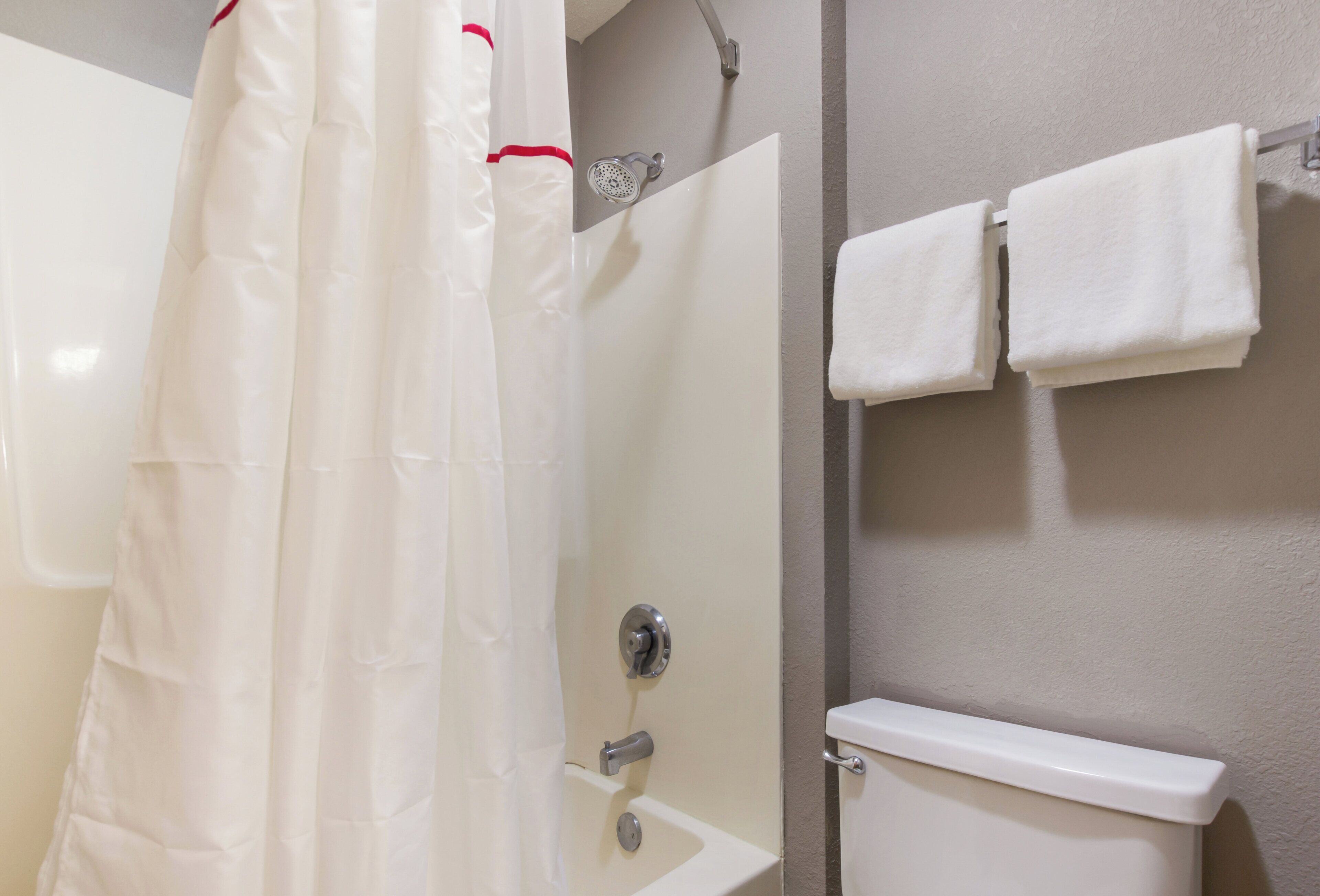 A bathroom with a shower curtain, a toilet, and a towel rack.