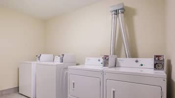 Un lavadero con cuatro lavadoras y secadoras Whirlpool blancas, un sistema de ventilación en la parte superior y un panel de control con una etiqueta de precio.