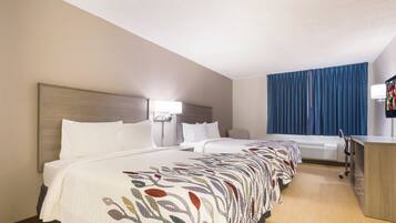 A hotel room with two beds, a desk, and a television.