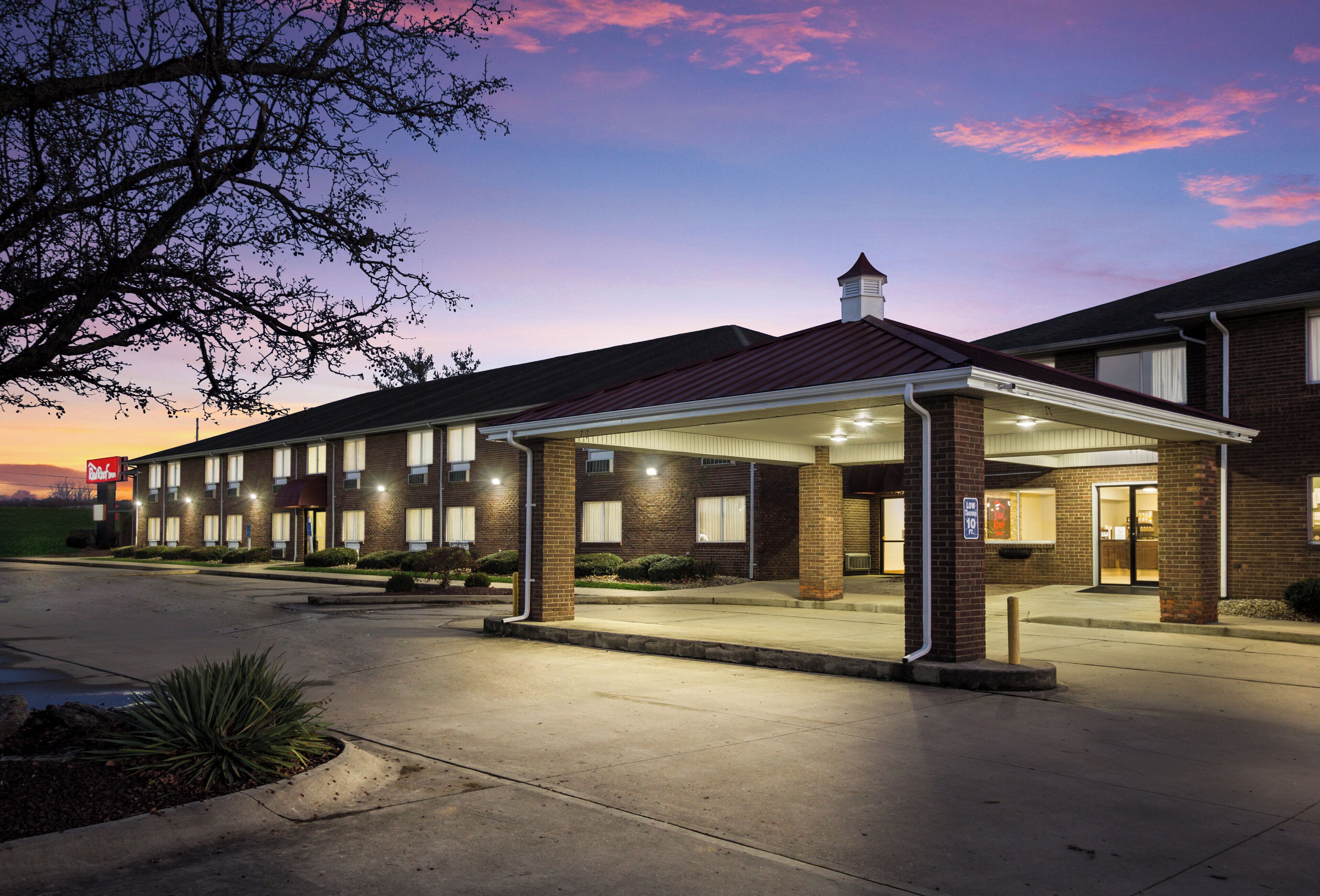 A hotel with a covered entrance, multiple windows, and a brick facade.