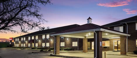 A hotel with a covered entrance, multiple windows, and a brick facade.