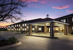 A hotel with a covered entrance, multiple windows, and a brick facade.