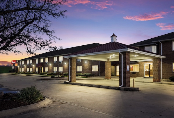 A hotel with a covered entrance, multiple windows, and a brick facade.