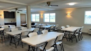 A spacious room with multiple tables and chairs, ceiling fans, and windows providing natural light. - Red Roof Inn Lawrenceburg (Lawrenceburg)