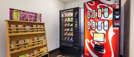 A hallway with a vending machine stocked with snacks and a visitors' guide shelf.