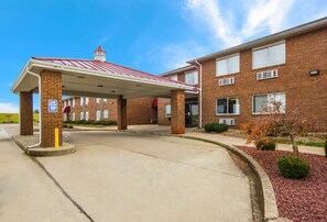 A two-story brick building with a covered parking area and a small garden with red mulch. - Red Roof Inn Lawrenceburg (Lawrenceburg)