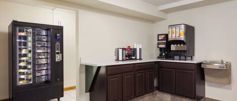 A kitchenette with a beverage vending machine, a coffee machine, and a water dispenser.