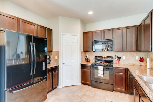 Enjoy cooking in this fully equipped kitchen with a refrigerator, microwave, and oven, and access to a spacious living area.