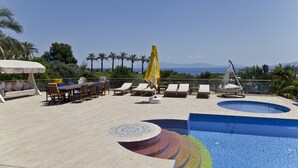 A rooftop pool area with lounge chairs, a dining table, and a yellow umbrella. - Palmiye Tepesi (Bodrum)
