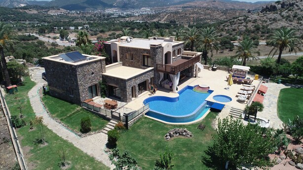 A large house with a swimming pool, stone exterior, and a view of the surrounding landscape. - Palmiye Tepesi (Bodrum)