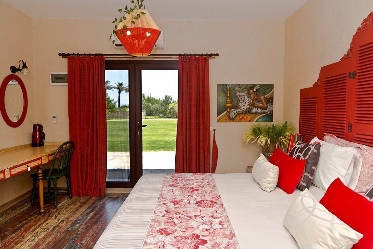 A hotel room with a bed, a desk, and a view of the outdoors.