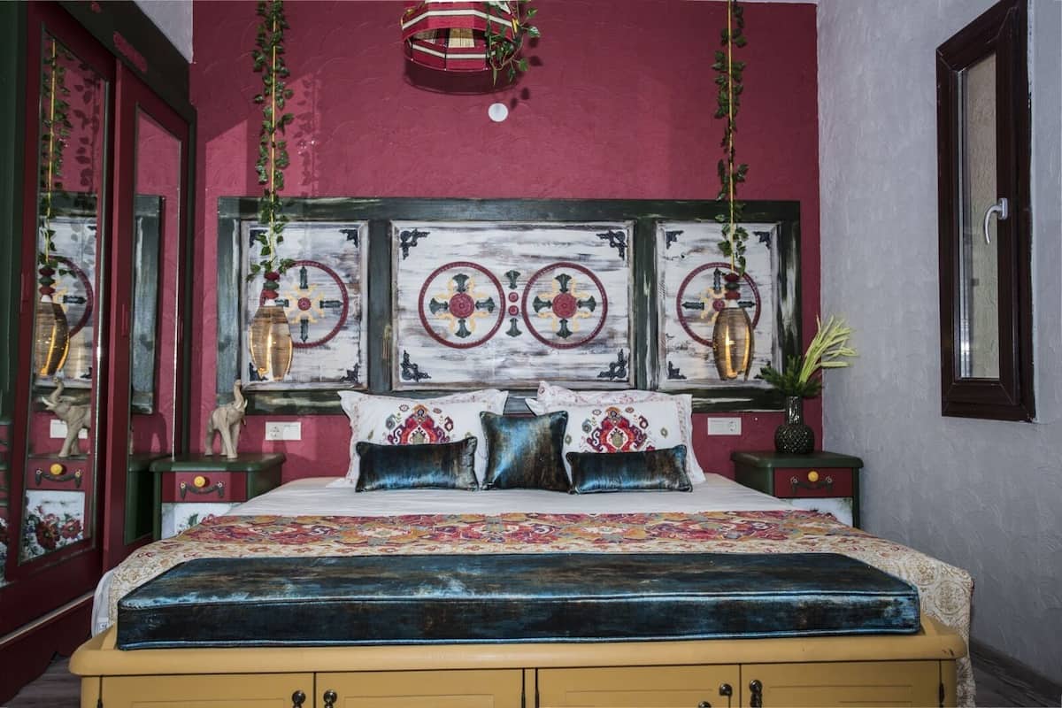 A bedroom with a bed, decorative pillows, a nightstand, and a wall with artwork.