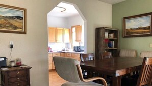 A dining area with a wooden table and chairs, a small side table, and a bookshelf.