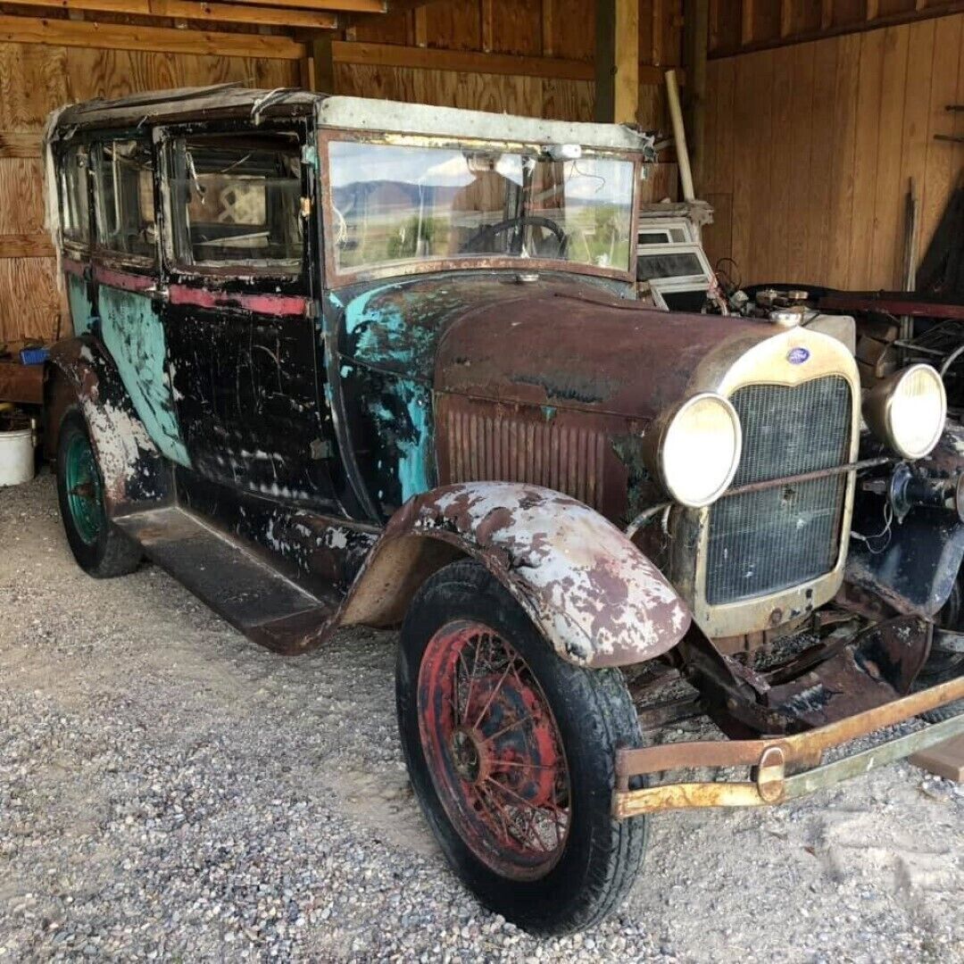 An old, rusted car with visible damage and missing parts, parked inside a wooden structure.