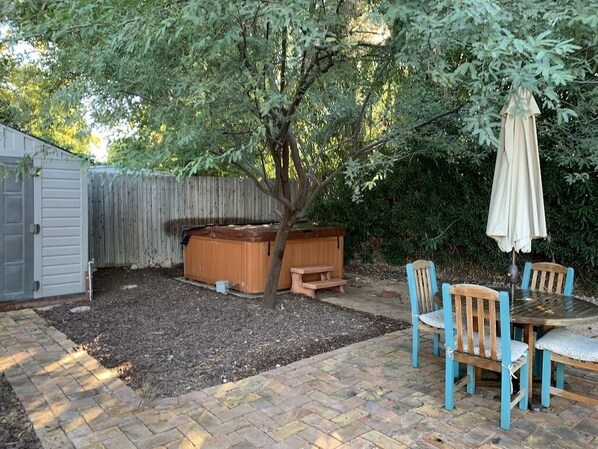 Un patio trasero con jacuzzi, terraza de madera y zona de estar al aire libre.