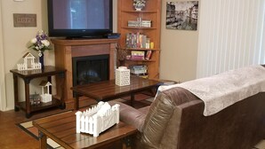 Una sala de estar con televisión, estanterías, chimenea y un sofá.