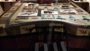 Una cama bien hecha con colcha de estampados de animales, flanqueada por dos lámparas de noche y un reloj digital.