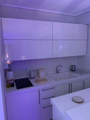 A modern kitchen with white cabinets, a sink, and a countertop with various items.