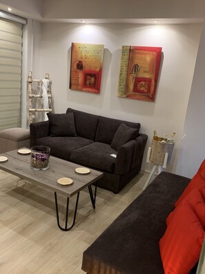 A modern living room with a grey sofa, a wooden coffee table, and two paintings on the wall.