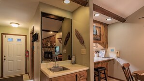 Una cocina con armarios de madera, un lavamanos y una zona de comedor con una mesa y sillas de madera.