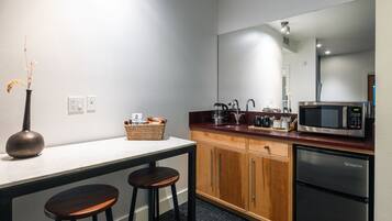 Eine kompakte Küche mit Kühlschrank, Mikrowelle und einer kleinen Essecke mit Hockern.