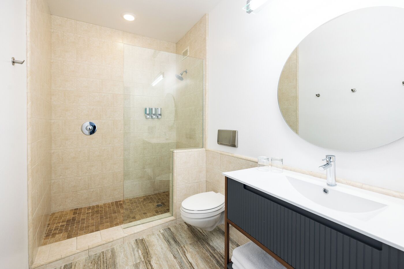 A modern bathroom with a glass-enclosed shower, a toilet, a sink with a mirror, and a towel rack.