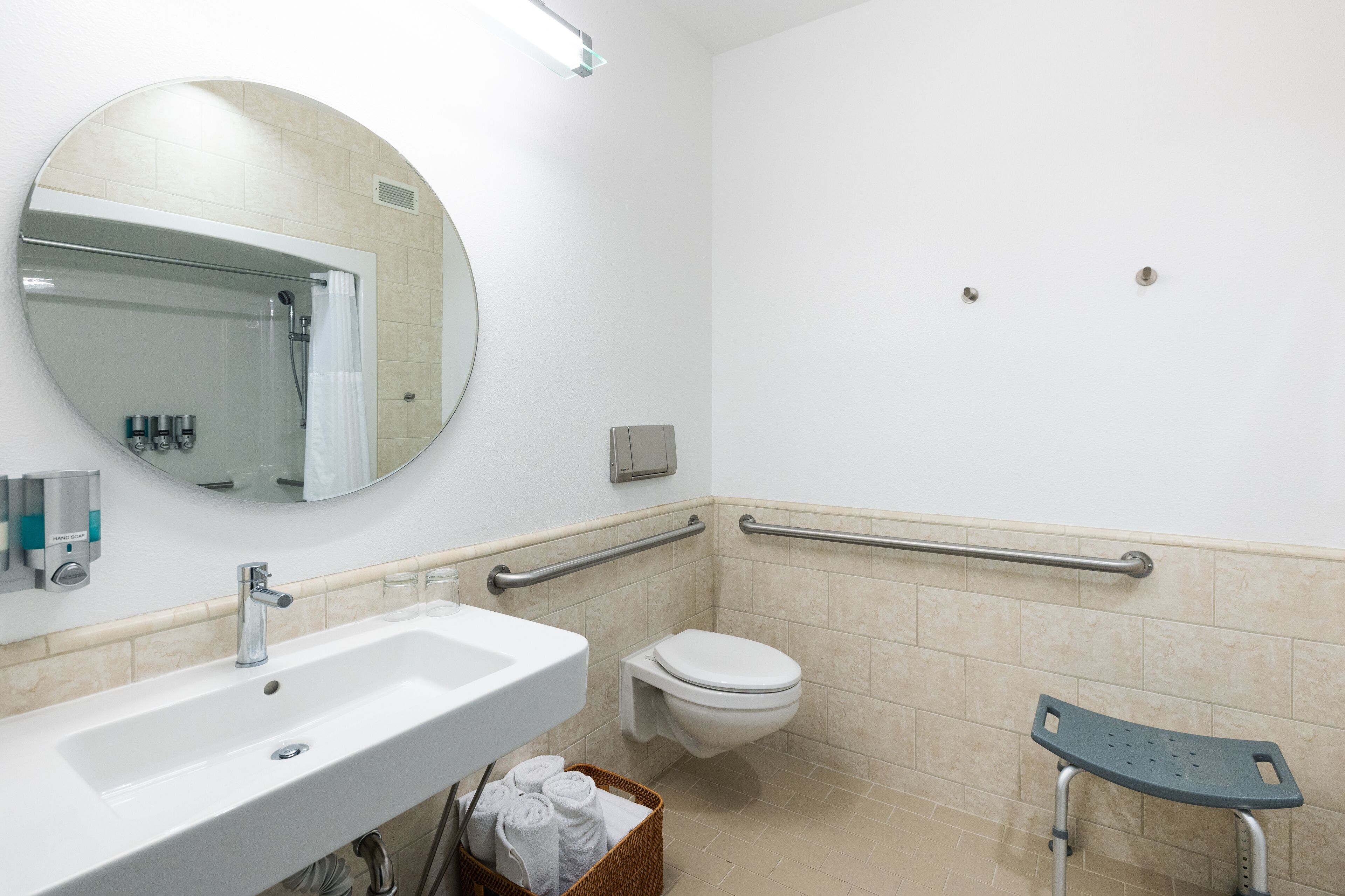 A bathroom with a sink, toilet, mirror, and grab bars.