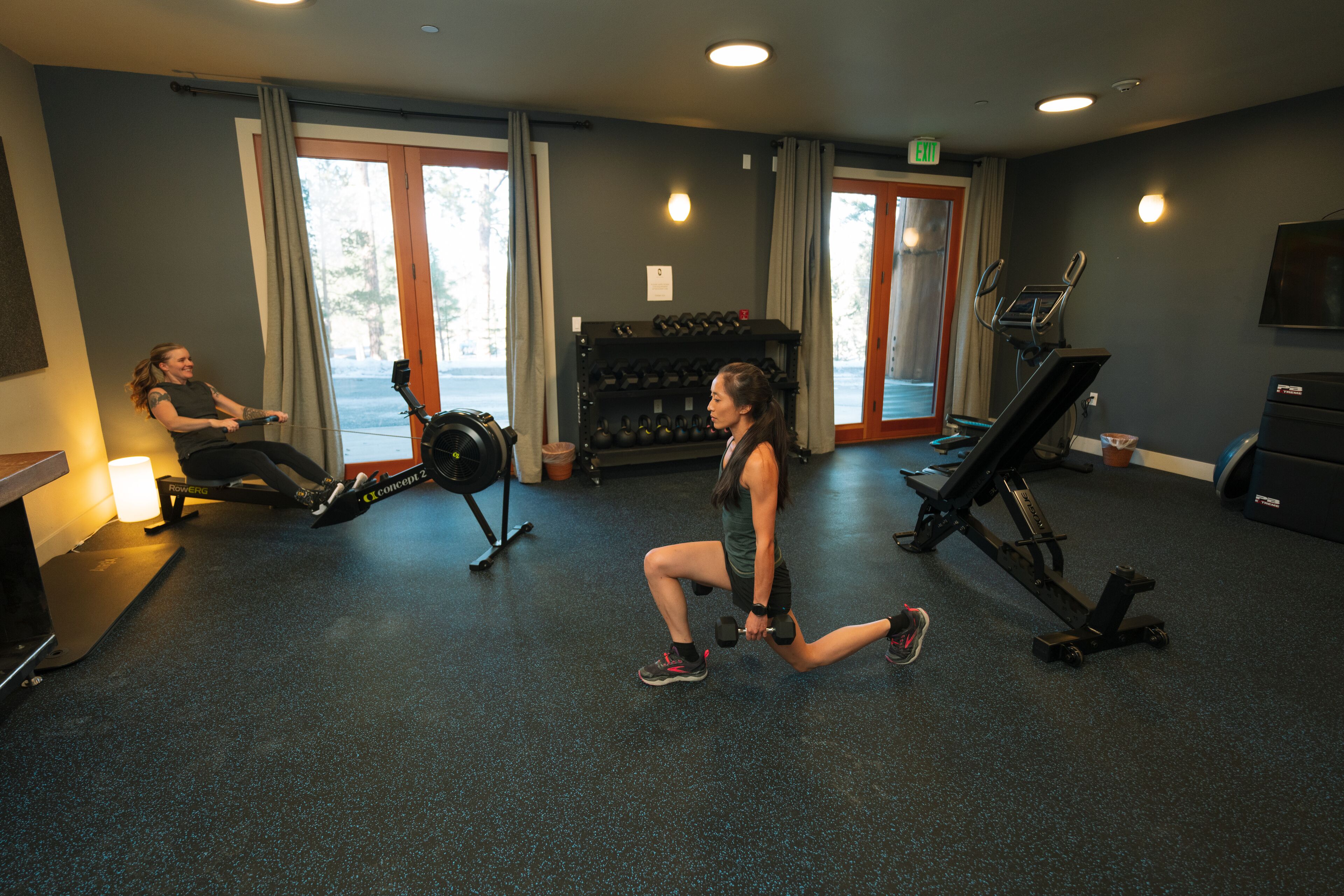 A gym with exercise equipment, a treadmill, and a seated woman.