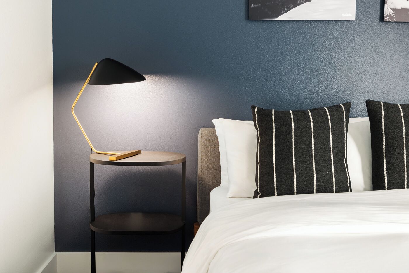 A neatly arranged bedroom with a bed, a bedside table with a lamp, and a chair.