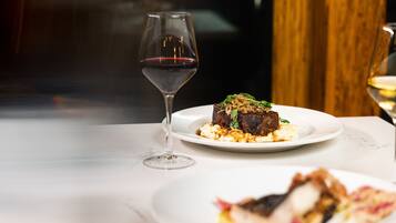 Una mesa de comedor con un plato de comida y una copa de vino.